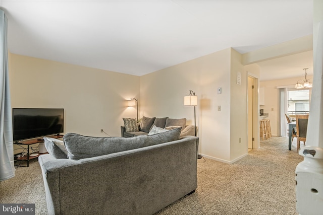 carpeted living room with an inviting chandelier