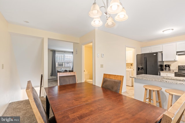 dining room featuring a chandelier and washer / dryer