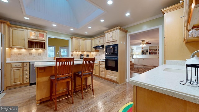 kitchen with sink, a kitchen bar, decorative backsplash, light brown cabinetry, and ornamental molding