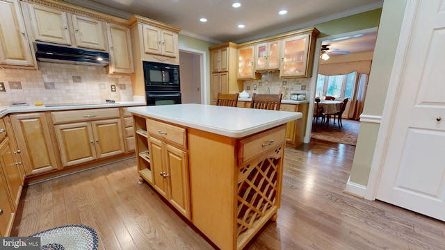 kitchen featuring decorative backsplash, ornamental molding, ceiling fan, black appliances, and a center island