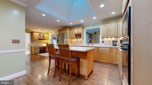 kitchen with a breakfast bar, sink, light wood-type flooring, and backsplash