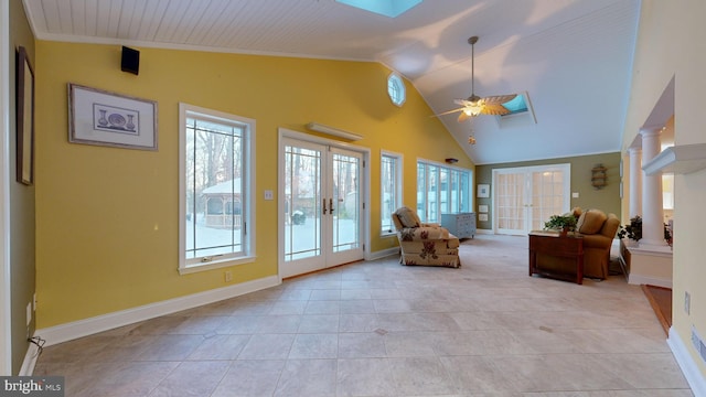 interior space featuring vaulted ceiling with skylight, ceiling fan, ornate columns, and french doors