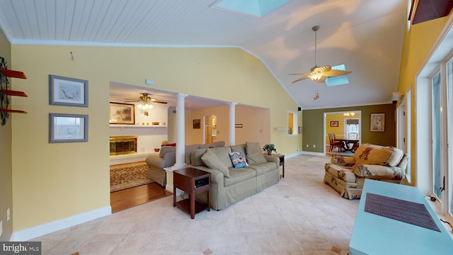 living room with ornate columns, ceiling fan, and vaulted ceiling with skylight