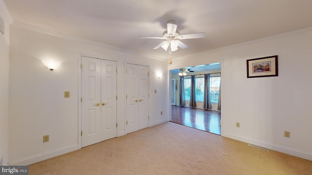 empty room featuring ceiling fan, light colored carpet, and ornamental molding