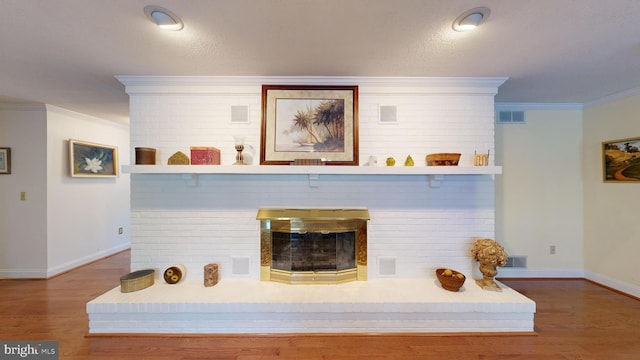 room details featuring a brick fireplace, hardwood / wood-style flooring, and ornamental molding