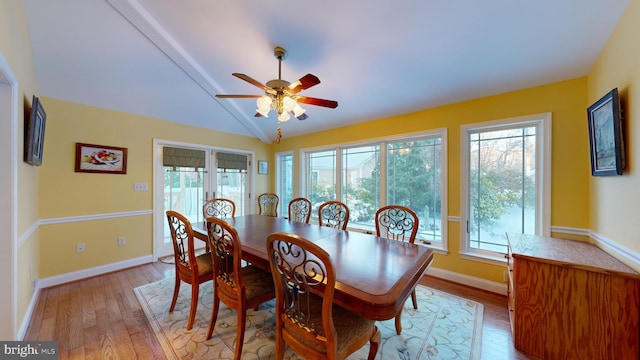 dining room with ceiling fan, a healthy amount of sunlight, vaulted ceiling, and light wood-type flooring