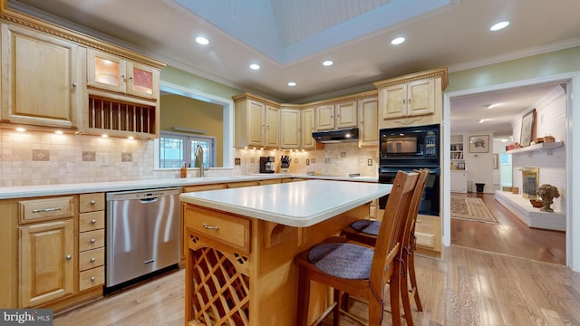 kitchen featuring backsplash, black appliances, sink, a kitchen island, and a kitchen bar