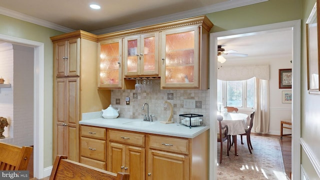 kitchen featuring ceiling fan, ornamental molding, sink, and tasteful backsplash