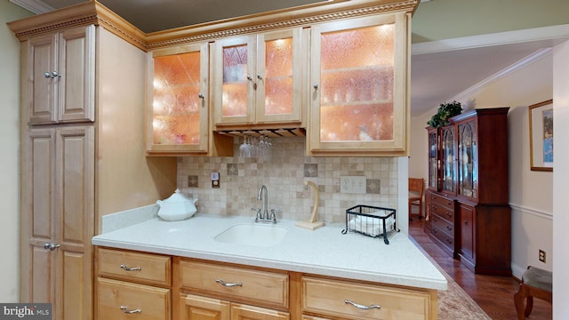 kitchen with light brown cabinetry, tasteful backsplash, crown molding, and sink