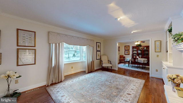 living area featuring ceiling fan, wood-type flooring, and ornamental molding