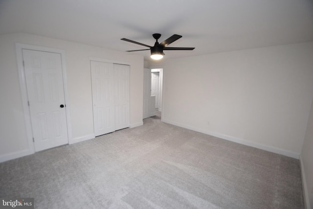 unfurnished bedroom featuring light carpet, ceiling fan, and multiple closets