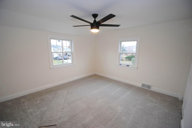 empty room with carpet flooring, ceiling fan, and plenty of natural light