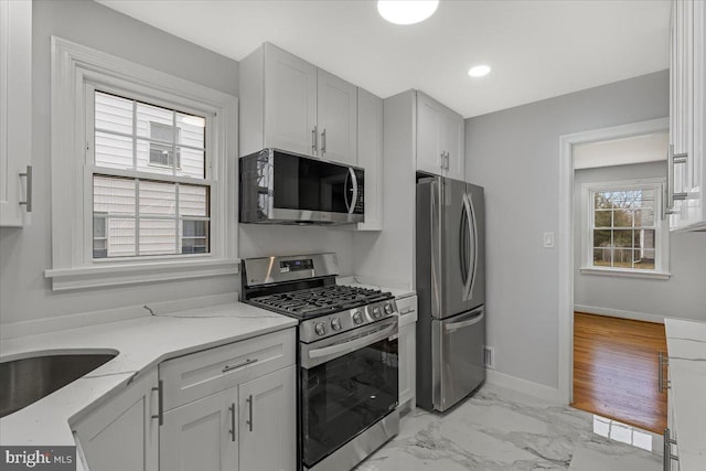 kitchen featuring stainless steel appliances, light stone countertops, and sink