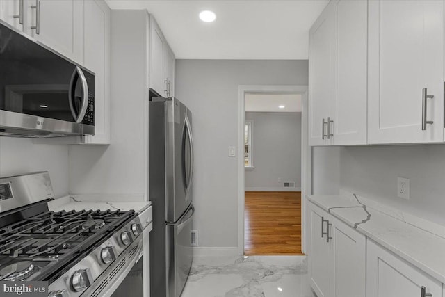 kitchen with light stone counters, stainless steel appliances, and white cabinets