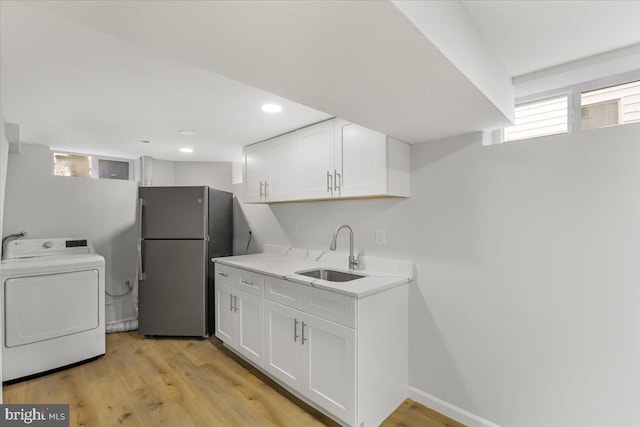 laundry area with washer / clothes dryer, sink, and light hardwood / wood-style flooring