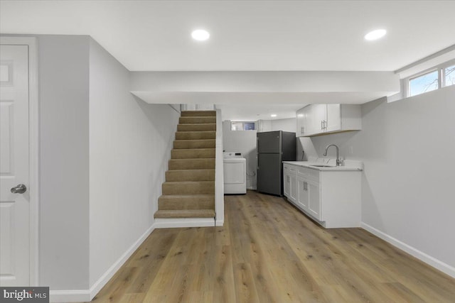 kitchen featuring washer / clothes dryer, sink, white cabinets, and black fridge