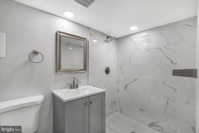 bathroom featuring vanity, toilet, and tiled shower