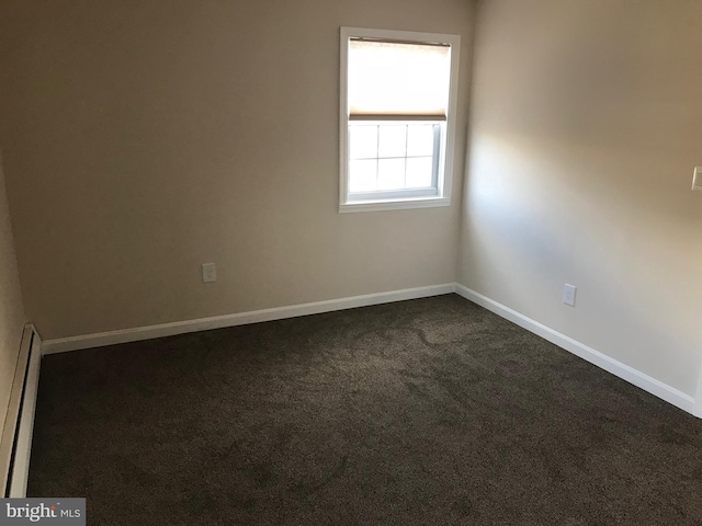 carpeted spare room with a baseboard heating unit