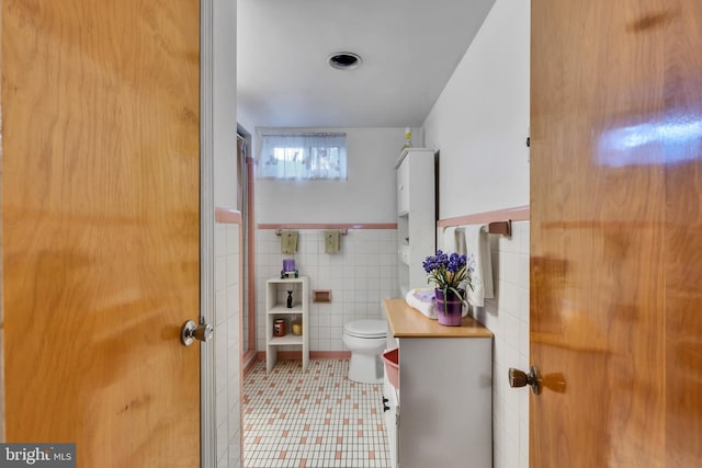 bathroom with toilet and tile walls