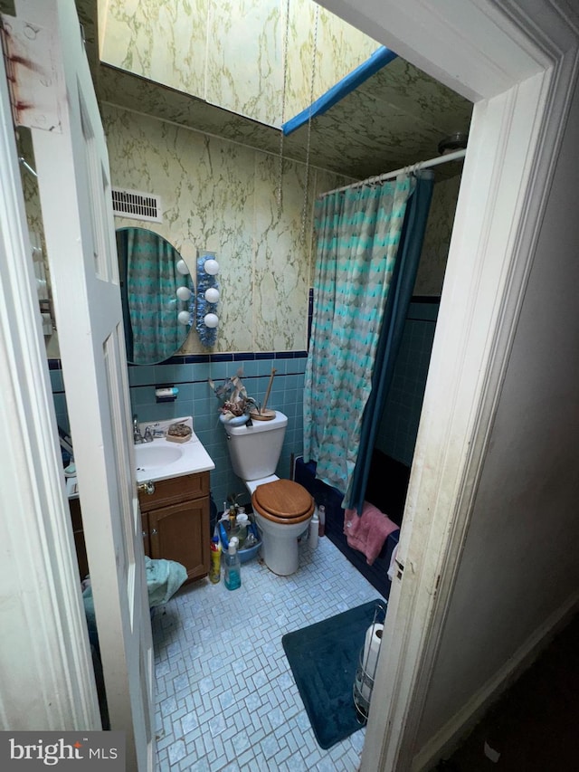 bathroom with vanity, tile patterned flooring, toilet, tile walls, and curtained shower