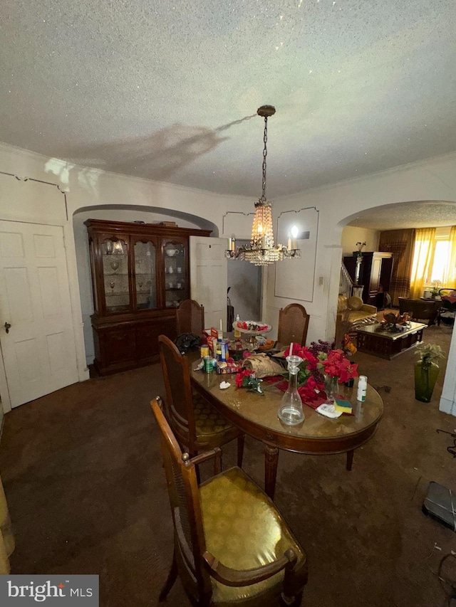 dining area with carpet floors, a textured ceiling, and an inviting chandelier