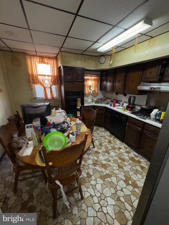 kitchen featuring dark brown cabinets, oven, a drop ceiling, and exhaust hood