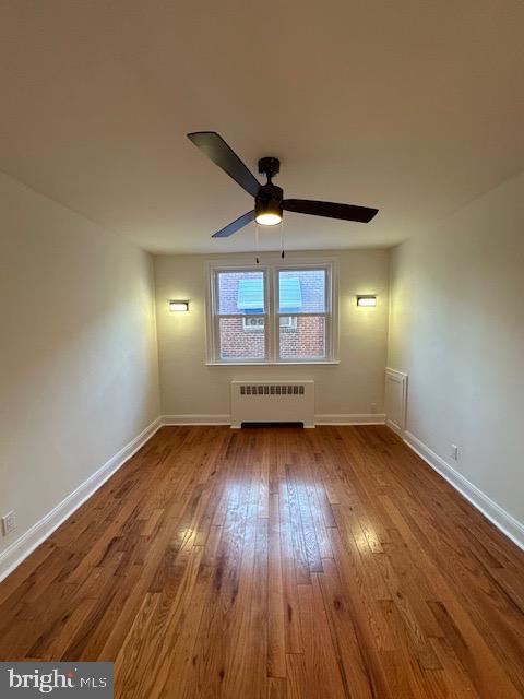 empty room featuring radiator heating unit, ceiling fan, and wood-type flooring