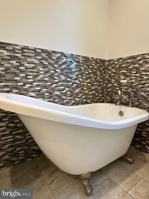 bathroom featuring a bath and tile walls