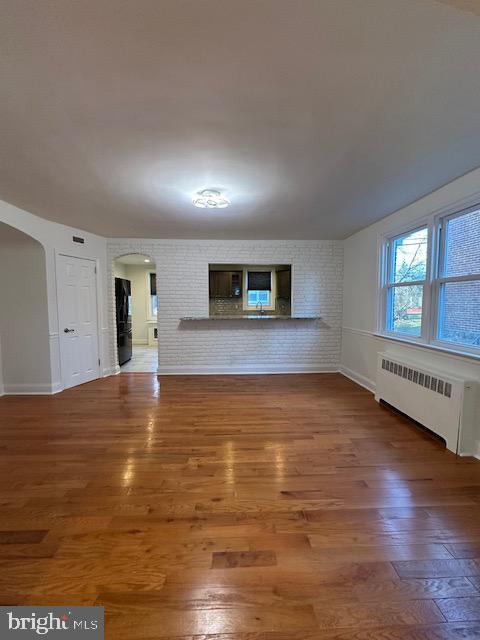 unfurnished living room with radiator heating unit and wood-type flooring