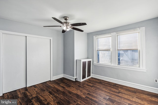 unfurnished bedroom with ceiling fan, dark wood-type flooring, and a closet