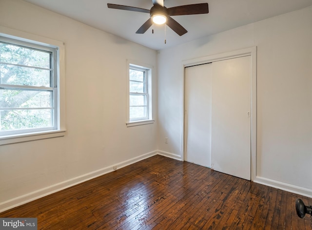 unfurnished bedroom featuring multiple windows, ceiling fan, a closet, and dark wood-type flooring