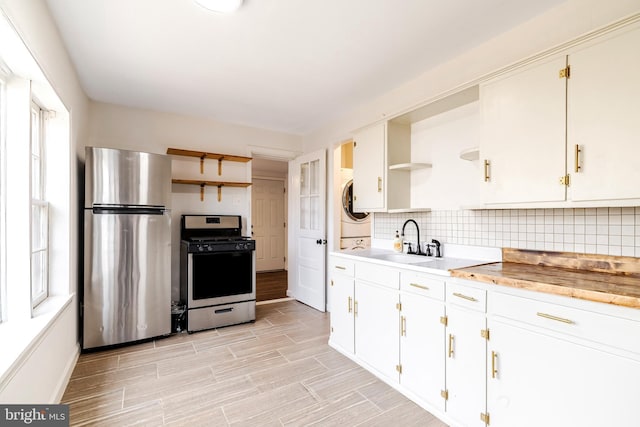 kitchen with tasteful backsplash, sink, white cabinets, and appliances with stainless steel finishes