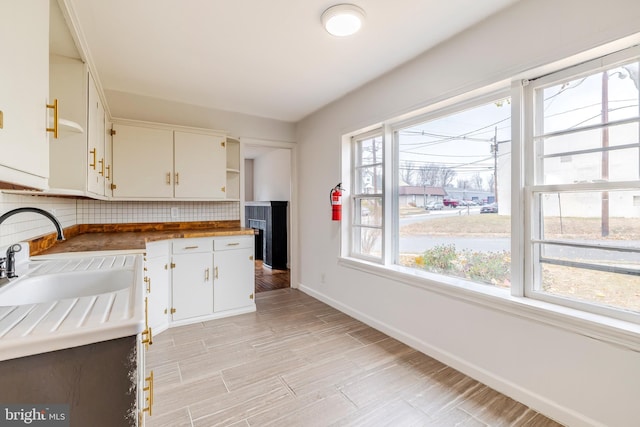 kitchen featuring wooden counters, white cabinetry, sink, and tasteful backsplash