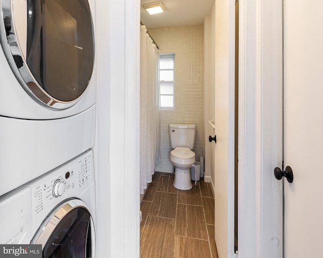 laundry room with tile walls and stacked washer and clothes dryer