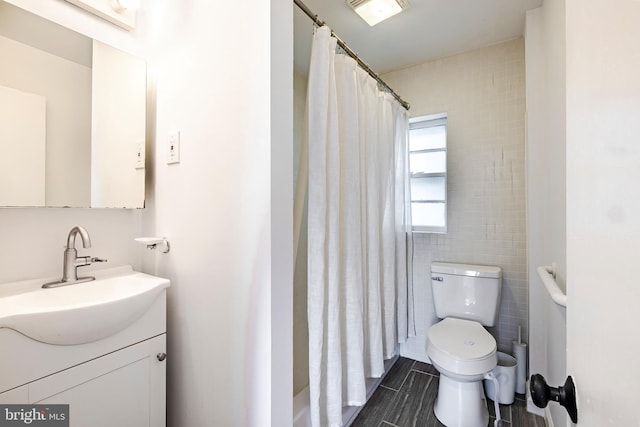 bathroom with vanity, curtained shower, toilet, and tile walls