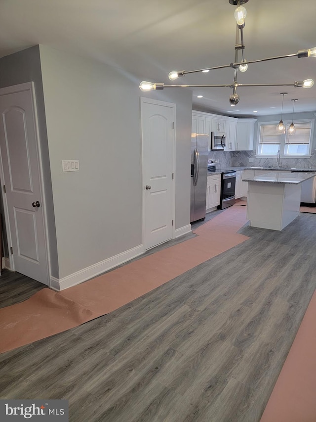 kitchen featuring pendant lighting, a center island, hardwood / wood-style flooring, appliances with stainless steel finishes, and white cabinetry