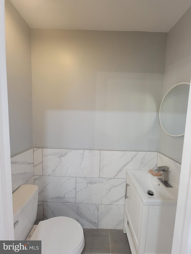 bathroom featuring tile patterned flooring, vanity, toilet, and tile walls