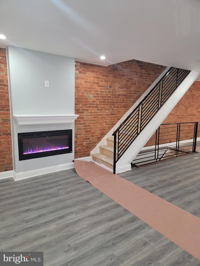 stairs with wood-type flooring and brick wall