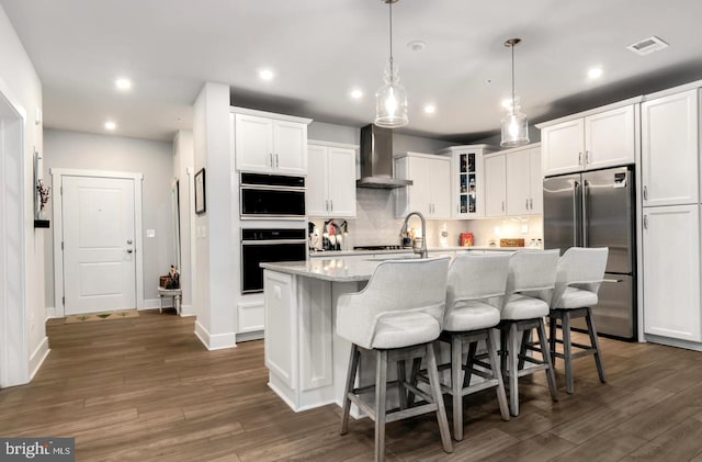 kitchen featuring pendant lighting, a center island with sink, wall chimney exhaust hood, high end fridge, and dark hardwood / wood-style flooring