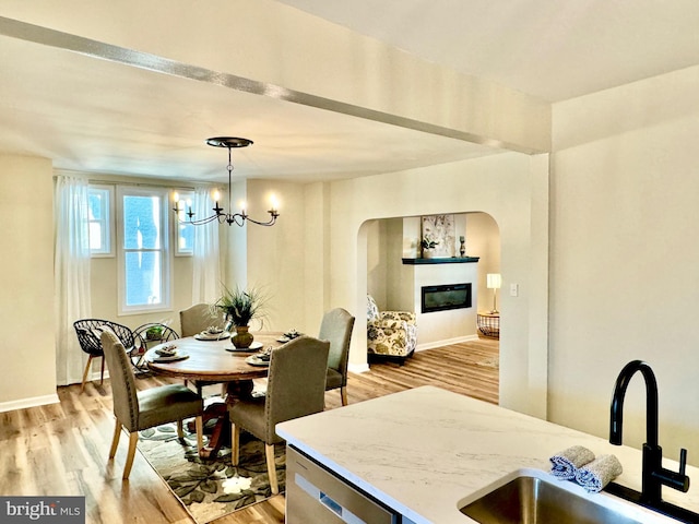 dining area with a chandelier, sink, and light hardwood / wood-style flooring