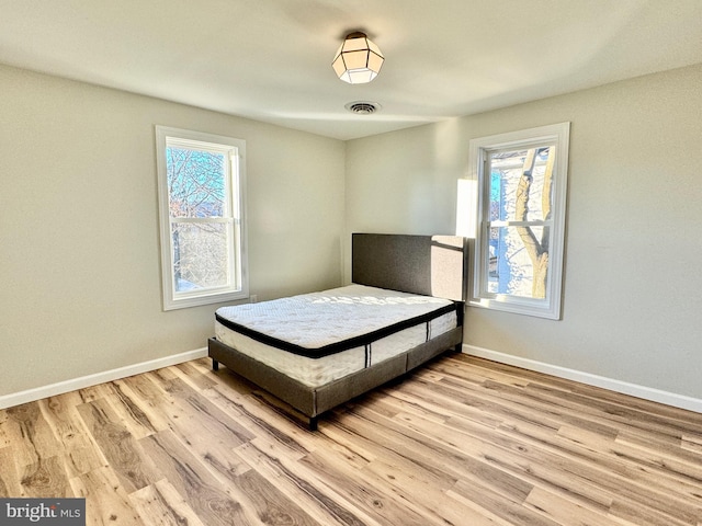 bedroom with multiple windows and light wood-type flooring