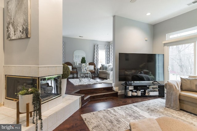 living room with a tiled fireplace and hardwood / wood-style flooring