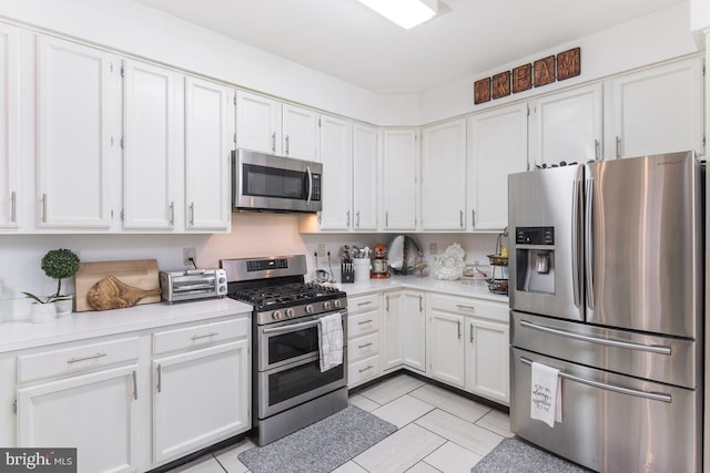 kitchen featuring light tile patterned flooring, white cabinets, and stainless steel appliances