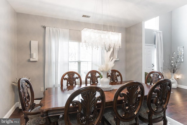 dining room with dark wood-type flooring and a notable chandelier