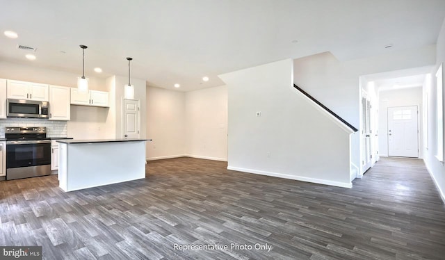 kitchen featuring appliances with stainless steel finishes, backsplash, pendant lighting, dark hardwood / wood-style floors, and white cabinetry