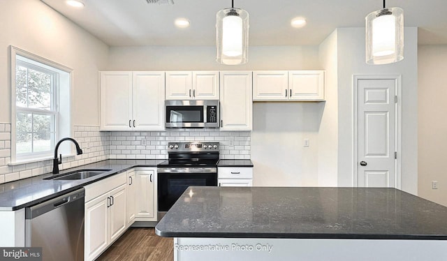 kitchen with appliances with stainless steel finishes, white cabinetry, hanging light fixtures, and sink