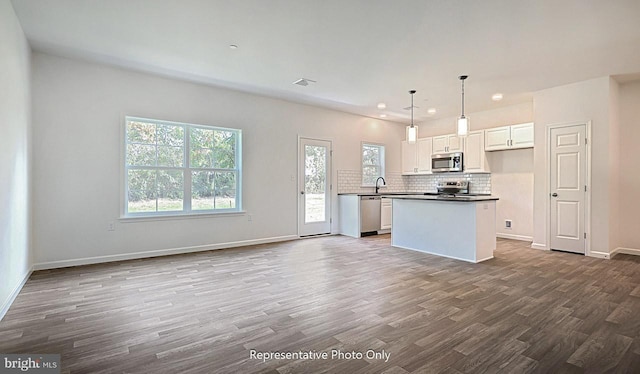 kitchen with white cabinetry, stainless steel appliances, dark hardwood / wood-style floors, pendant lighting, and a kitchen island