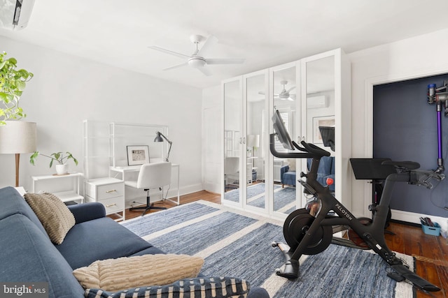 workout room featuring wood-type flooring, a wall unit AC, and ceiling fan