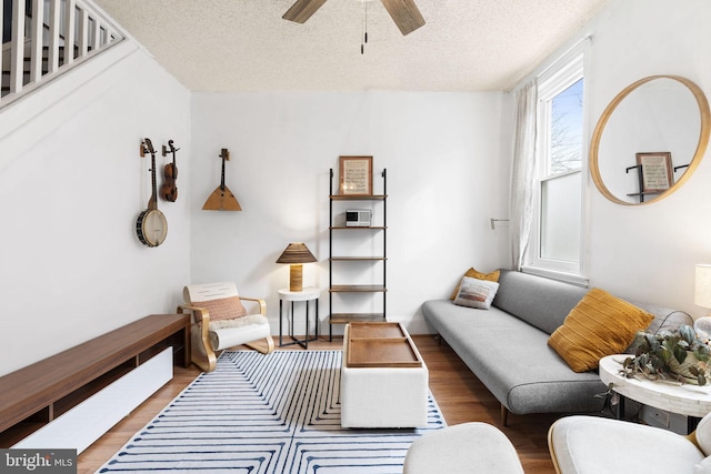 living room with ceiling fan, hardwood / wood-style flooring, and a textured ceiling