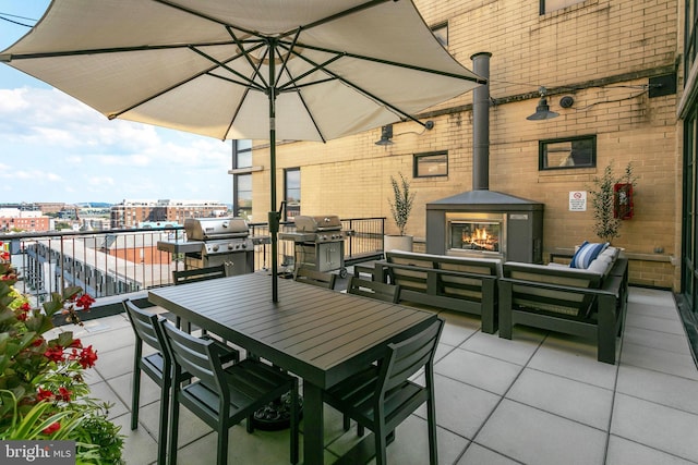 view of patio with a view of city, an outdoor living space with a fireplace, outdoor dining area, and a grill